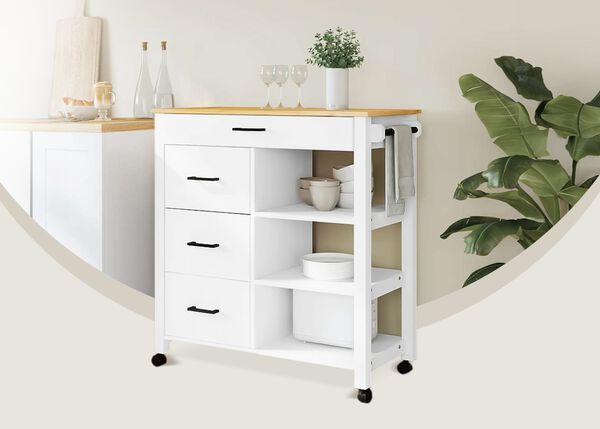 Chariot de rangement blanc avec &eacute;tag&egrave;res, tiroirs et plateau en bois, plac&eacute; dans un coin de cuisine d&eacute;cor&eacute; &agrave; c&ocirc;t&eacute; d&rsquo;une grande plante verte.