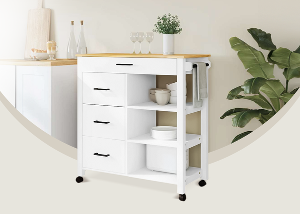 Chariot de rangement blanc avec &eacute;tag&egrave;res, tiroirs et plateau en bois, plac&eacute; dans un coin de cuisine d&eacute;cor&eacute; &agrave; c&ocirc;t&eacute; d&rsquo;une grande plante verte.