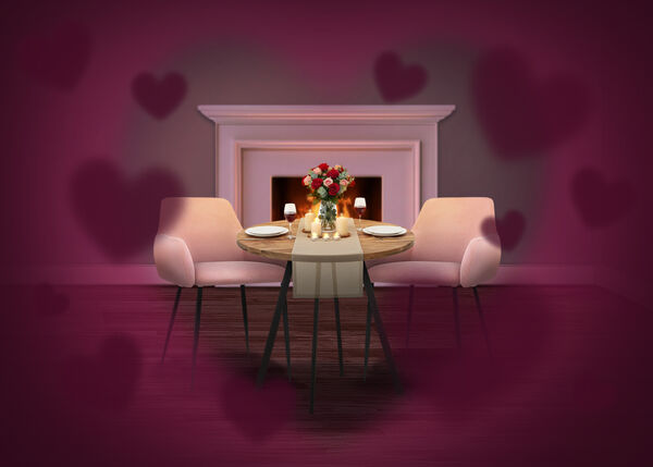 Mise en sc&egrave;ne romantique avec une petite table ronde dress&eacute;e pour deux, des chaises rembourr&eacute;es roses, des bougies et un bouquet de roses, plac&eacute;e devant une chemin&eacute;e allum&eacute;e, avec des formes de c&oelig;urs douces cr&eacute;ant une ambiance de Saint-Valentin.