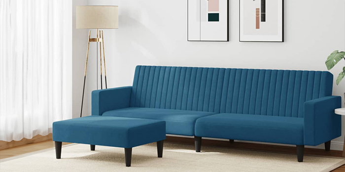 Un canapé deux places bleu marine avec repose-pieds assorti, accompagné d’une plante verte, d’un lampadaire derrière et d’un tableau décoratif au mur. Cliquez pour découvrir plus de nouveautés.