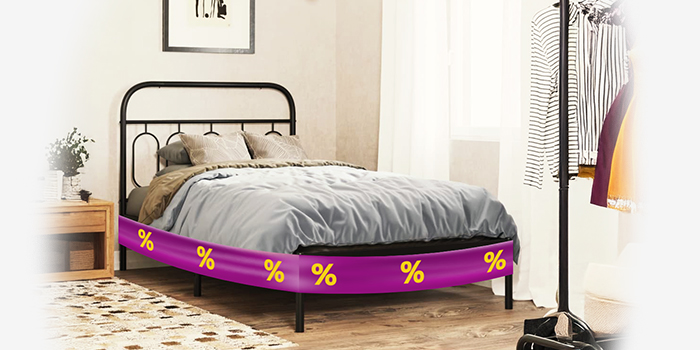 Cadre de lit en métal noir avec couette et oreillers gris, entouré d'une bande promotionnelle violette affichant des icônes de réduction jaunes, à côté d'une table de chevet en bois, dans une chambre à coucher stylée. Cliquez pour découvrir la collection.