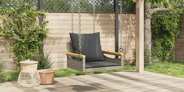 Fauteuil suspendu en rotin avec coussins foncés, suspendu à une poutre en bois sur une terrasse. Cliquez pour voir les produits de la collection. 